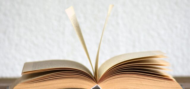 Close-up image of an open book with pages turning, creating a dynamic visual.