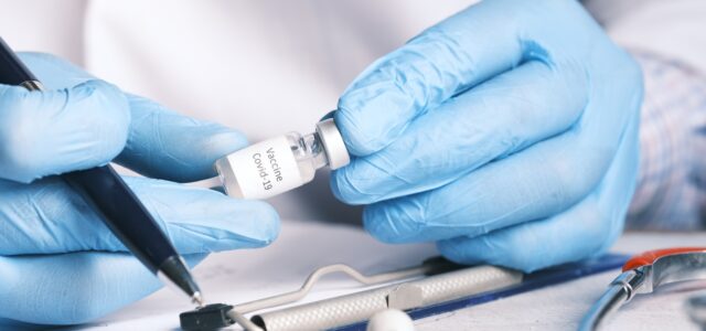 person in blue gloves holding white usb cable