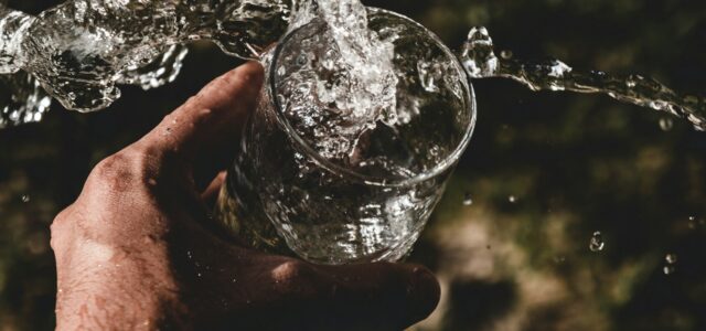 person holding drinking glass filled with water